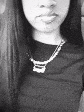 a black and white photo of a woman wearing a name necklace .