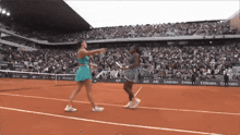 two female tennis players on a court with emirates banners
