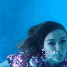 a woman in a purple sequined top is swimming underwater