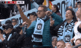 a man wearing a scarf that says ny stands in a crowd