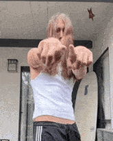 a man with long hair is standing on a porch and pointing at the camera .