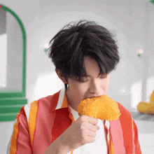 a young man eating a fried chicken wing