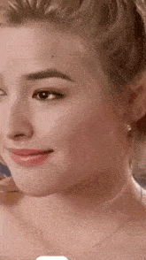 a close up of a woman 's face wearing a necklace and earrings