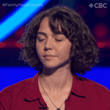 a woman with curly hair is sitting in front of a blue background with the letters cbc on it
