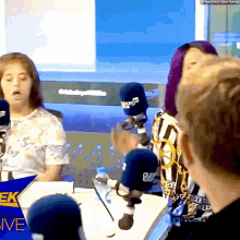 a group of people are sitting in front of microphones with the word live on the bottom right