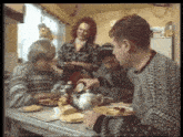 a group of people are sitting around a table with plates of food