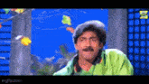 a man with a mustache is standing in front of a blue background .