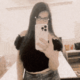 a woman wearing glasses is taking a selfie on her phone