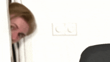 a man is peeking out from behind a door .