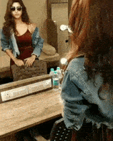 a woman sitting in front of a mirror with a bottle of water on the table