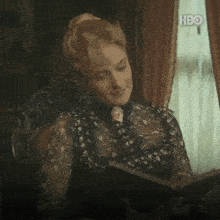 a woman sits in a chair reading a book with hbo written on the bottom right