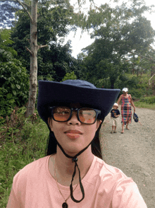 a woman wearing glasses and a hat takes a picture of herself