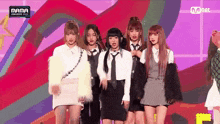 a group of girls are standing next to each other on a stage in front of a colorful background .