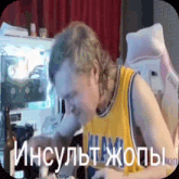a man in a yellow shirt is sitting in front of a computer and eating something .
