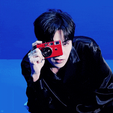 a man holding a red camera in front of his face