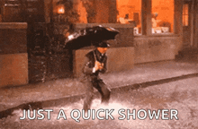 a man is running in the rain with an umbrella and the words `` just a quick shower '' behind him .