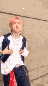 a young man with pink hair is standing in front of a wall .