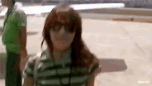a woman wearing sunglasses and a striped shirt is walking on a street .