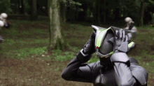 a person in a black and green costume is standing in the woods .
