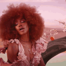 a woman with red hair is wearing a pink floral dress and holding a lollipop