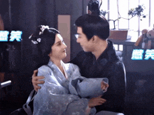 a man is holding a woman in his arms in front of a sign that says ' chinese ' on it