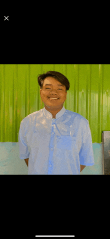 a young man in a blue shirt is smiling for the camera .