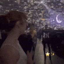 a woman in a white tank top is standing in a crowded stadium .