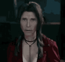 a woman with long hair is wearing a red jacket and a choker .