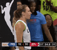 a female basketball player stands in front of a scoreboard that says min 92 90 atl 54.8 09