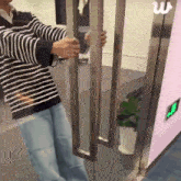 a man in a striped shirt is opening a door with the letter w on the bottom