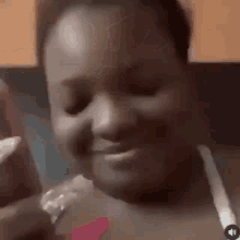 a woman is eating a piece of food and smiling while sitting in a kitchen .