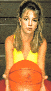 a woman in a yellow top is holding a basketball with the letter p on it