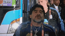 a man wearing an adidas shirt stands in front of a bus that says all areas team