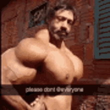 a shirtless man with huge muscles is standing in front of a brick building .