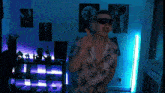 a man wearing sunglasses and headphones is dancing in front of a blue light
