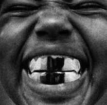 a black and white photo of a woman 's face with a cross in her mouth .