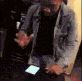 a man in a suit is standing in front of a table with a cell phone on it .