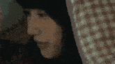 a close up of a woman 's face with a plaid pillow behind her head .