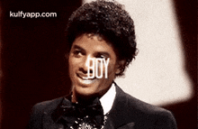a man in a suit and bow tie is smiling with the word boy written in front of him .