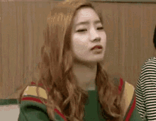a woman with long red hair is making a funny face while wearing a green sweater .