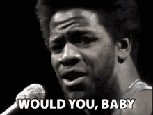 a man is singing into a microphone with the words `` would you , baby '' .
