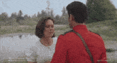 a man in a red uniform is kissing a woman in a white shirt