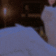 a blurry picture of a person laying on a bed with a lamp in the background
