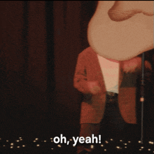 a man is standing in front of a microphone with the words oh yeah behind him