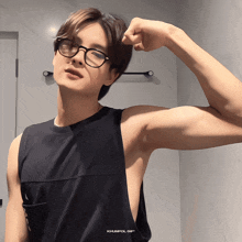 a man wearing glasses and a black tank top with khunpol gif written on it