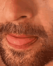 a close up of a man 's face with a beard and tongue sticking out .