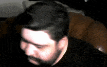 a man with a beard is sitting in a chair with his head down