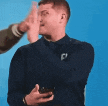 a man is holding a cell phone in his hand and pointing at it .