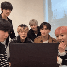 a group of young men are looking at a laptop computer