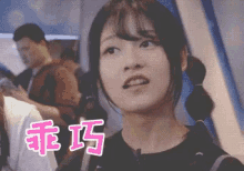 a girl with pigtails is looking at the camera with chinese writing behind her